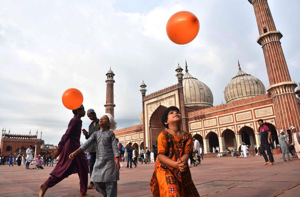 Indian children play with orange balloons