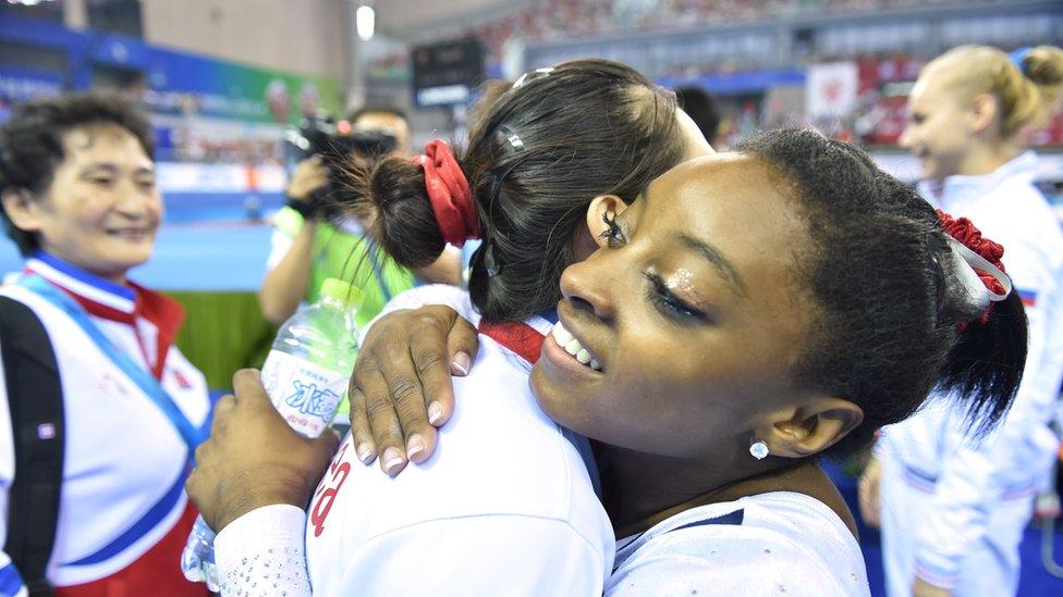 Hong Un-jong of North Korea (C) is congratulated by Simone Biles of the US (R) after their women's vault final at the gymnastics world championships in Nanning on October 11