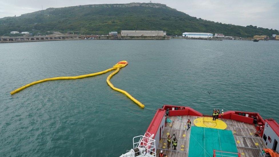 Yellow inflatable boom on the surface of the water in Portland Harbour