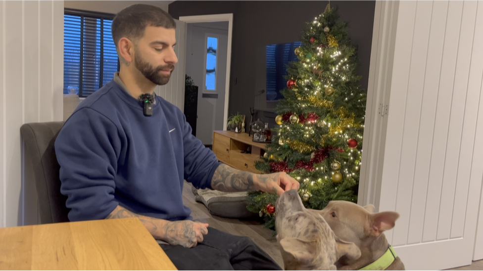 Richard feeds his dogs as they sit