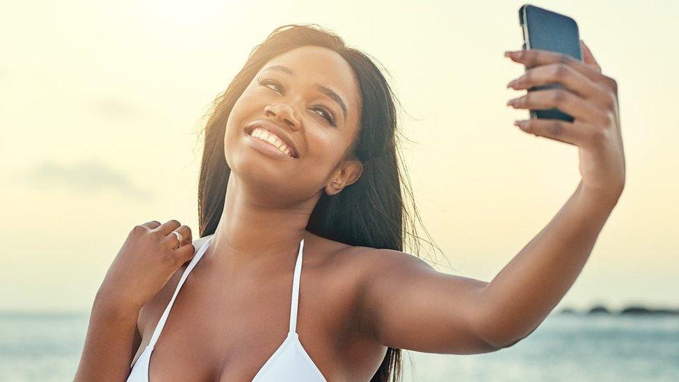 A woman takes a selfie on a beach