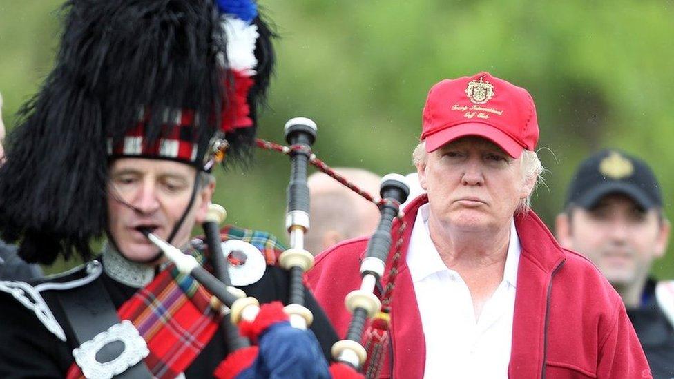 Donald Trump next to a man playing bagpipes at the opening of The Trump International Golf Links Course in July 2012