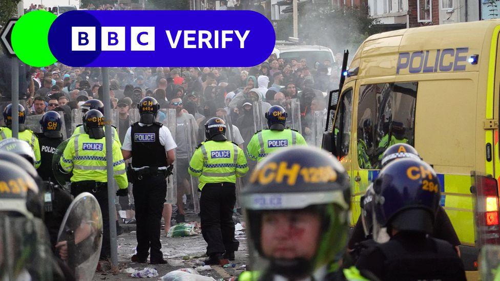 Police in riot gear facing a crowd of protestors in Southport