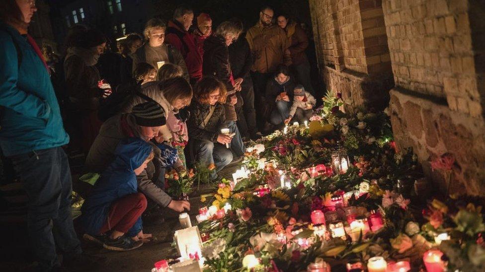 Mourners placing flowers and candles outside the synagogue