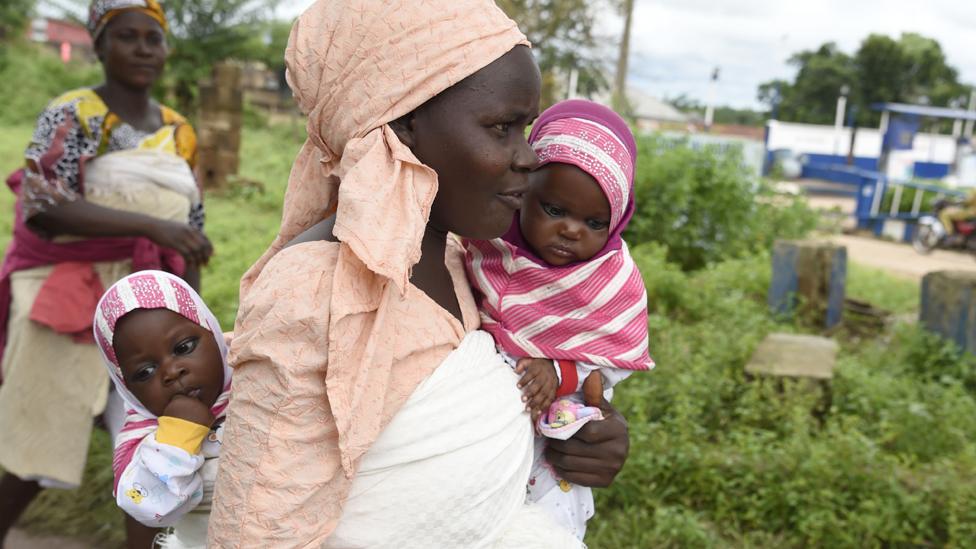 A mother holds her baby twins in Igbo-Ora, Nigeria - 2019