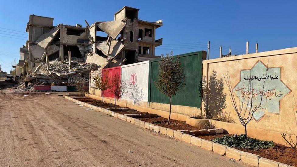 A dilapidated building at the top of a dusty road 