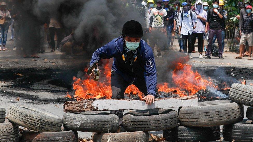 A man stands behind a barricade during a protest against the military coup, in Yangon, Myanmar March 27, 2021.