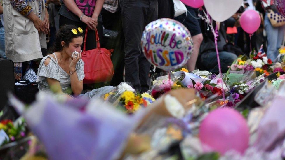 Woman weeps as she looks at the tributes