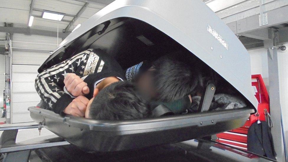 The three people lying inside the roof box