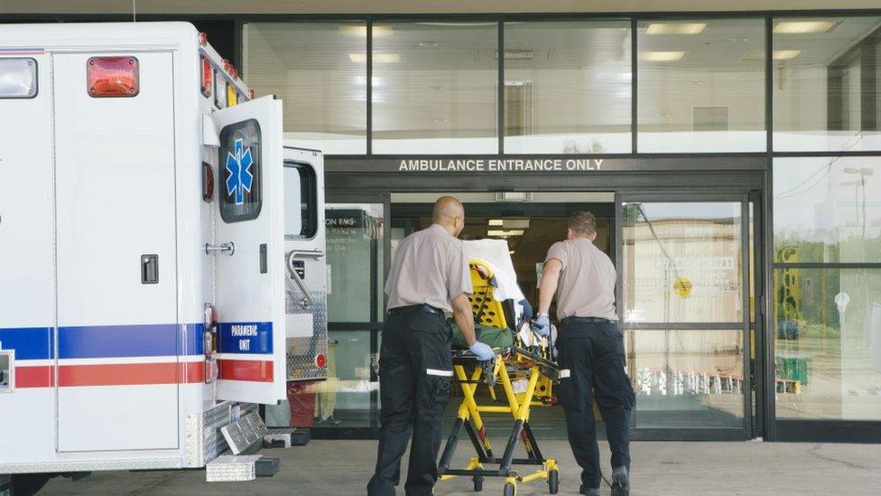 Paramedics bring an ambulance patients through the front of a hospital