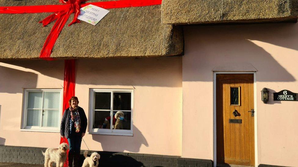 Michelle Young outside her cottage tied with a red ribbon