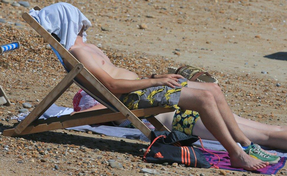 A man sunbathing on a deckchair on Brighton beach