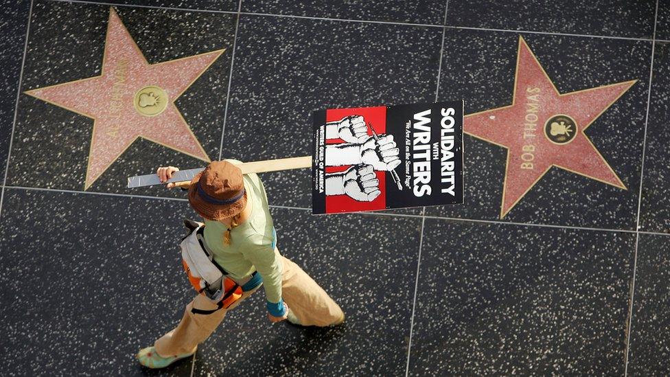 person walking past Hollywood stars.