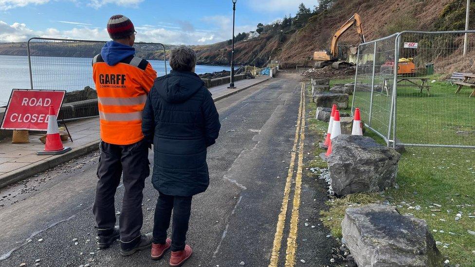 People watching a digger demolish the former cafe