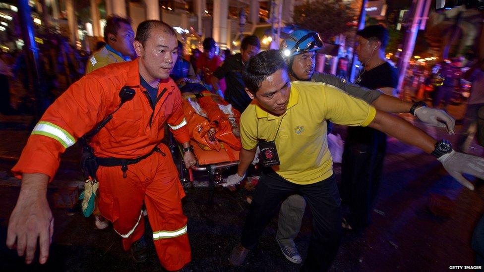 Thai rescue workers carry an injured person after a bomb exploded outside a religious shrine in central Bangkok on 17 August