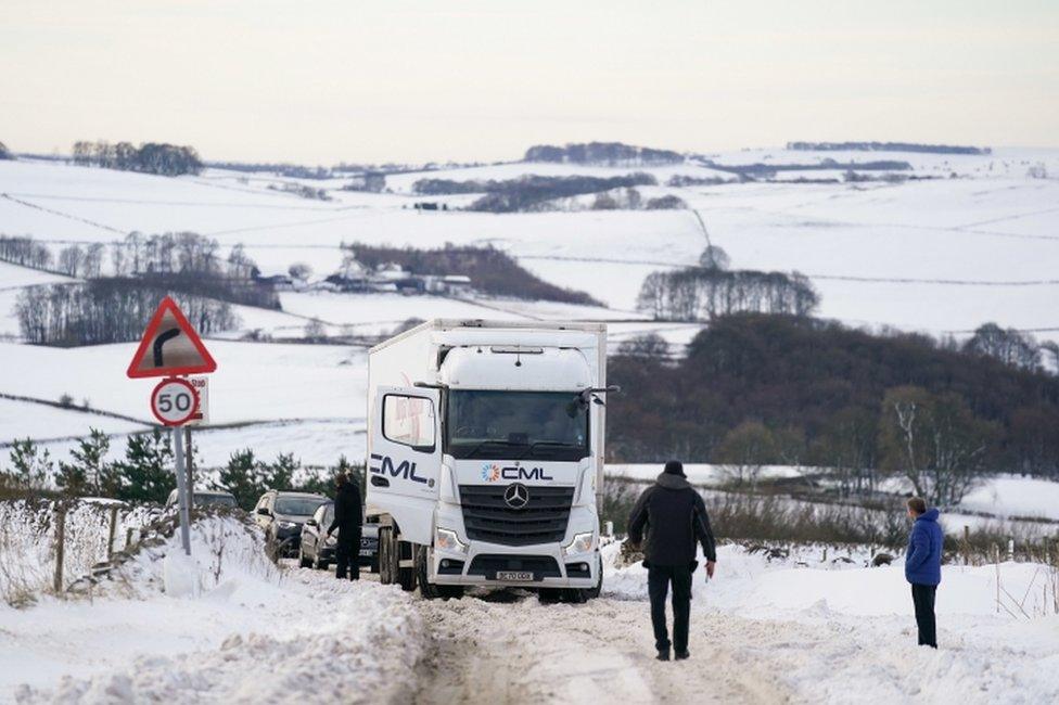 Motorists gather by a stuck HGV along the snow-covered A515 near Biggin, in the Peak District, Derbyshire, amid freezing conditions in the aftermath of Storm Arwen.