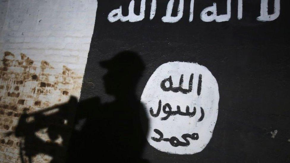 A member of the Iraqi forces walks past a mural bearing the logo of the Islamic State (IS) group in a tunnel that was reportedly used as a training centre by the jihadists, on March 1, 2017, in the village of Albu Sayf, on the southern outskirts of Mosul