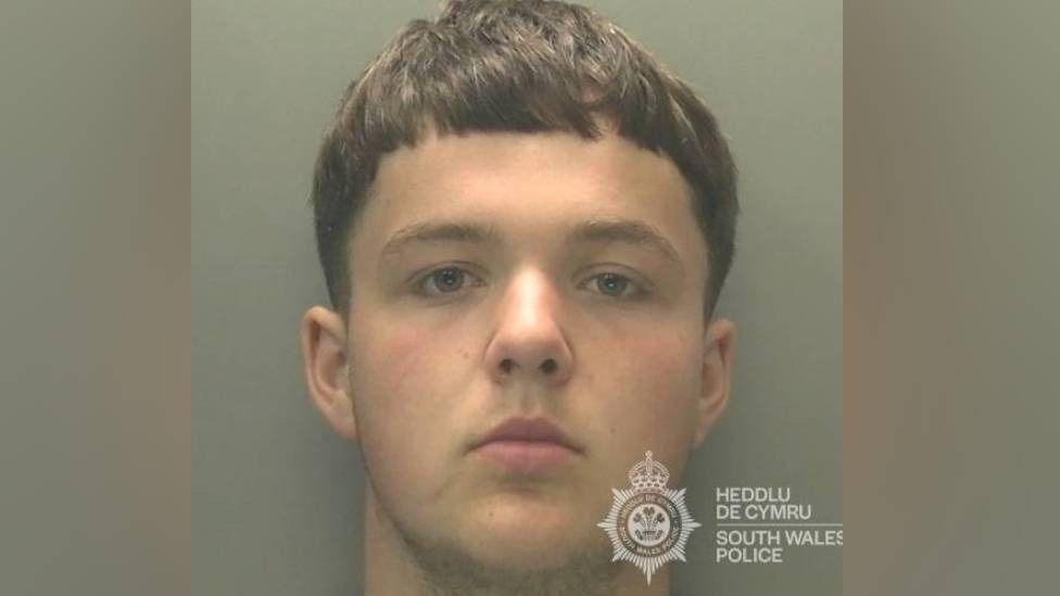 Police mugshot of a man with short mousy hair.