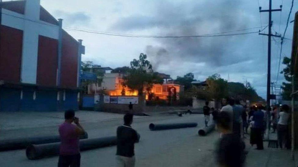 In this photograph taken on August 31, 2015, Indian people watch a blaze at the residence of Manipur state health minister, Phungzaphang Tonsimg which was torched during a protest against controversial tribal rights laws,