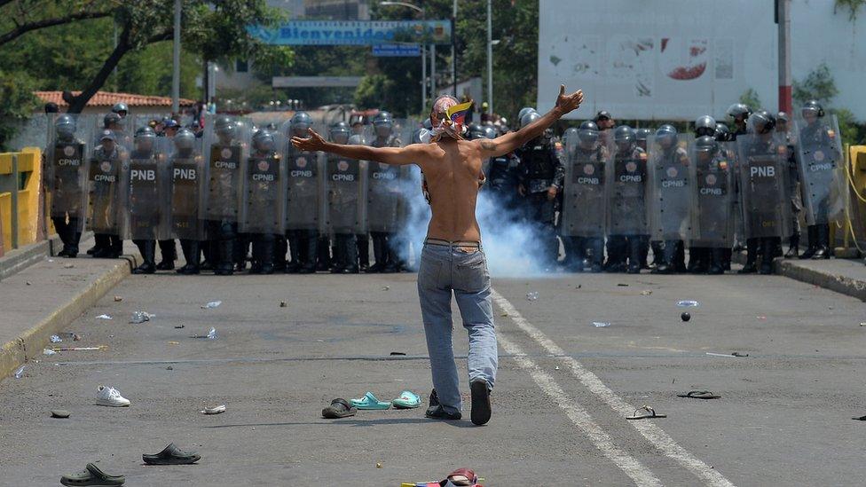 A demonstrator gestures in front of Venezuelan national policemen standing guard at the Simon Bolivar international bridge, in Cucuta