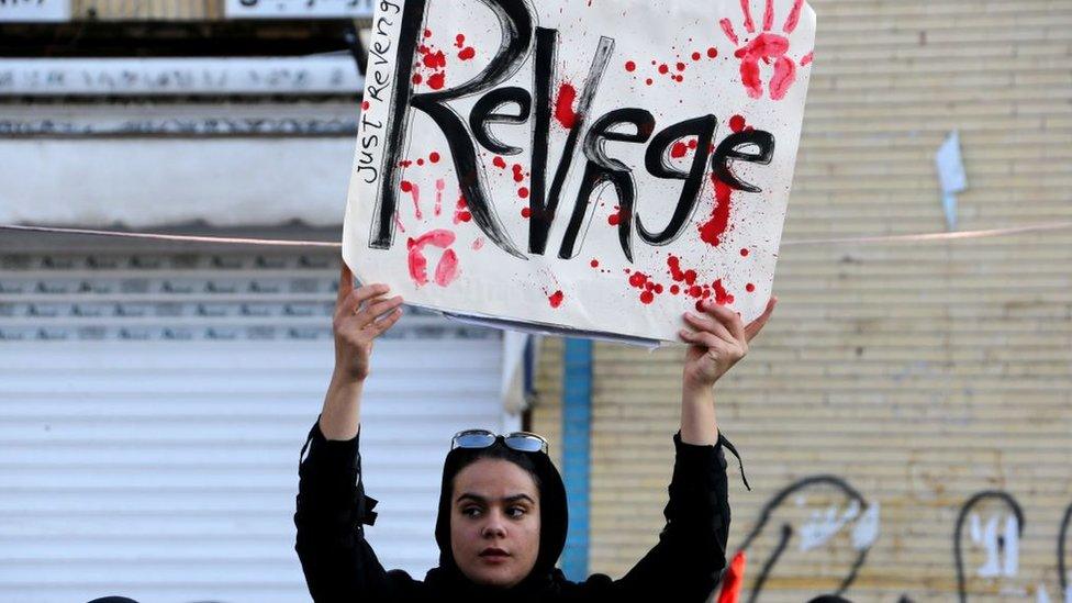 An Iranian mourner holds a placard during the final stage of funeral processions for the general Qasem Soleimani