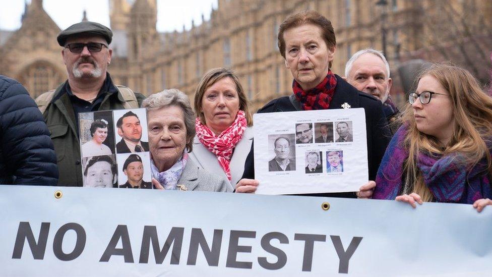 Demonstrators holding photos of their loved ones and a banner that says No Amnesty