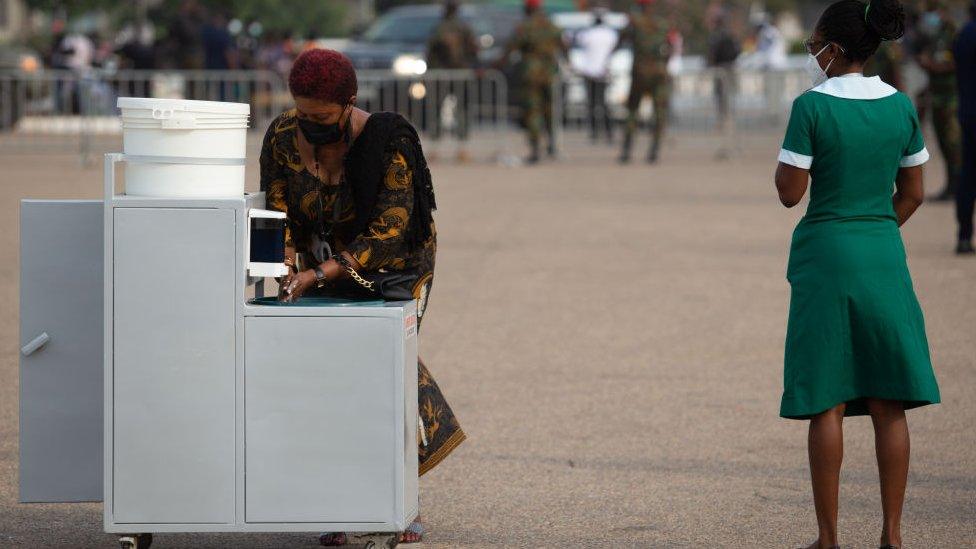 A nurse directs a woman to a hand washing station during the final funeral rites of former Ghana President Jerry John Rawlings in Accra, Ghana, on January 27, 2021. - Former Ghana President Jerry John Rawlings died in November 2020 at the age of 73 and his funeral was initially scheduled for December 23, 2020 but was postponed, due to what the foreign ministry called "unforeseen circumstances".