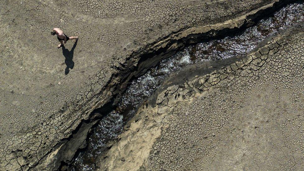 A man walks on the dry ground at Dowry reservoir, near to Oldham