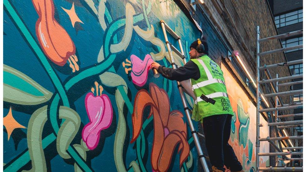 An artist works on the mural