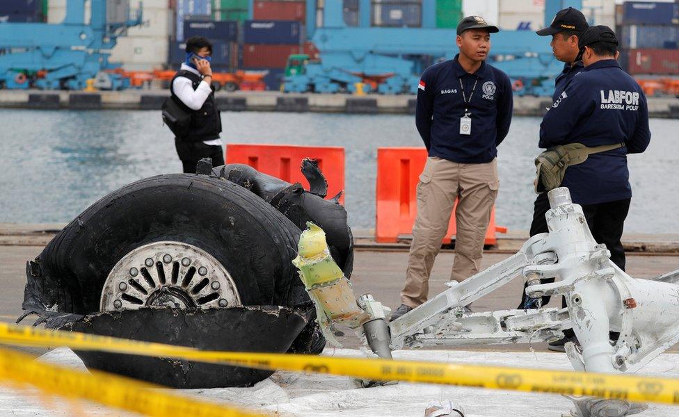 Indonesian forensic officers stand beside the damaged landing gear of Lion Air flight JT610 in Jakarta, 5 November 2018