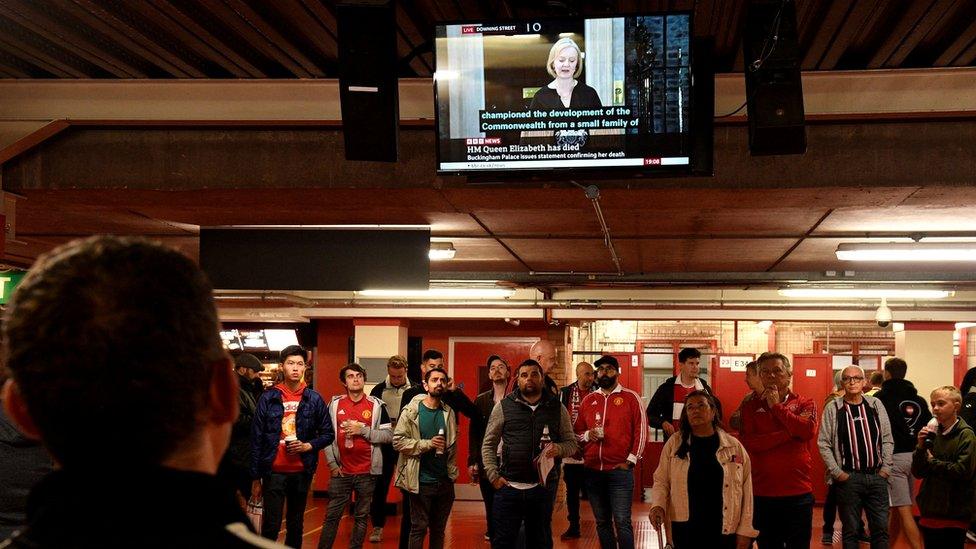 Footballs fans watch news about the Queen's death at Old Trafford