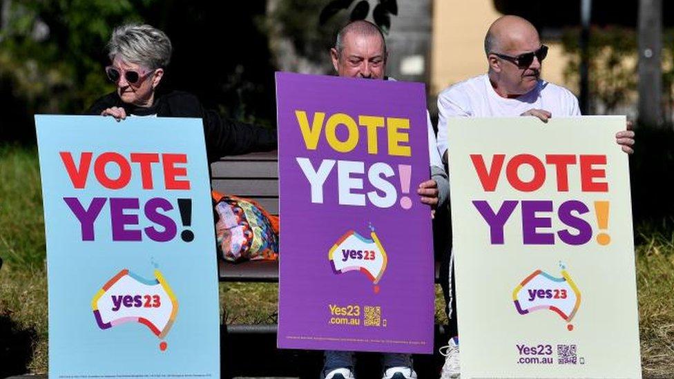 Supporters hold placards during a community event in support of an Indigenous Voice to Parliament