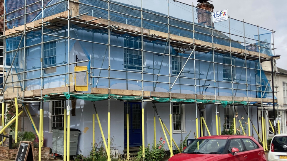 The outside of The Red Lion - a white building with scaffolding around it