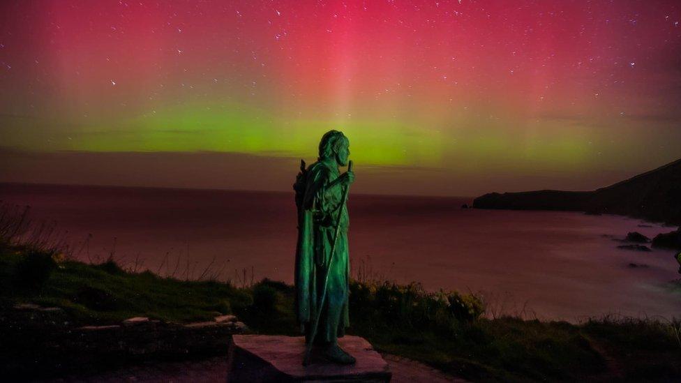 Northern lights behind St Crannog's Statue in Llangrannog, Ceredigion