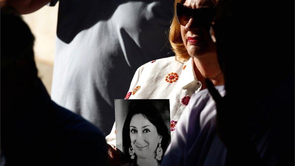 People hold up photos of anti-corruption journalist Daphne Caruana Galizia during a protest and vigil marking 21 months since her assassination, after three men were indicted for her murder, in Valletta, Malta, on 16 July 2019