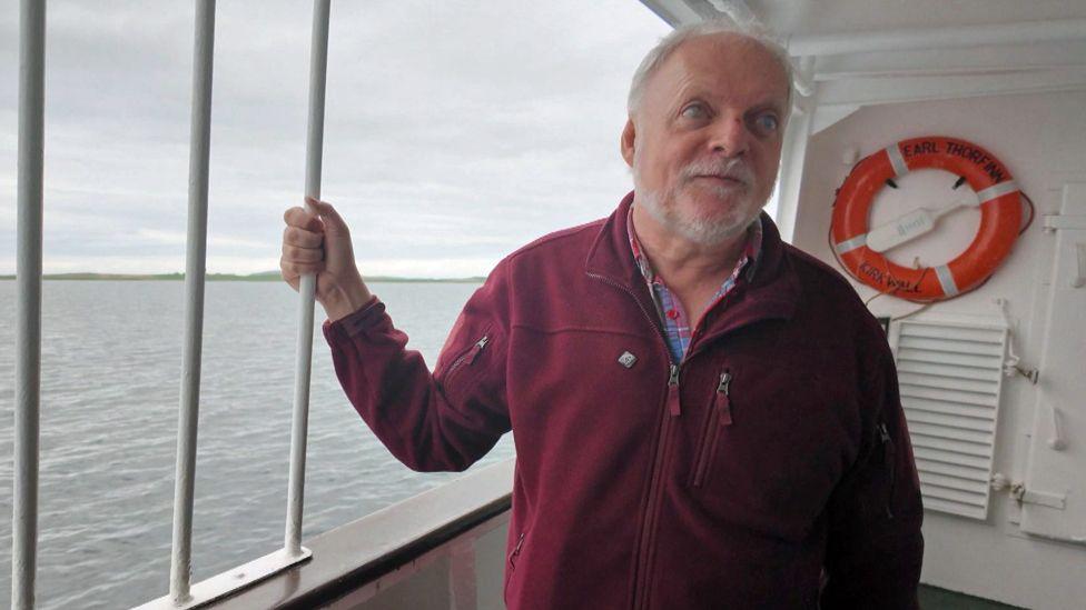 Ian Hamiton standing on board a ferry