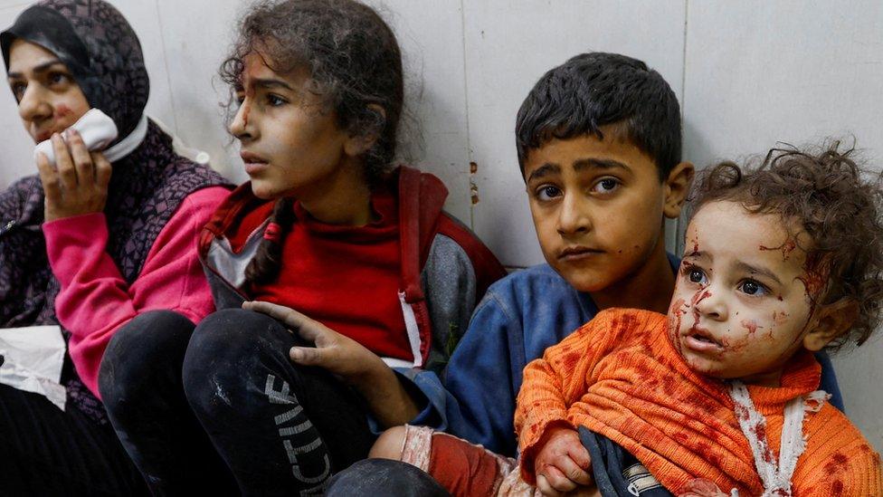 Three young children and a woman sitting inside a hospital