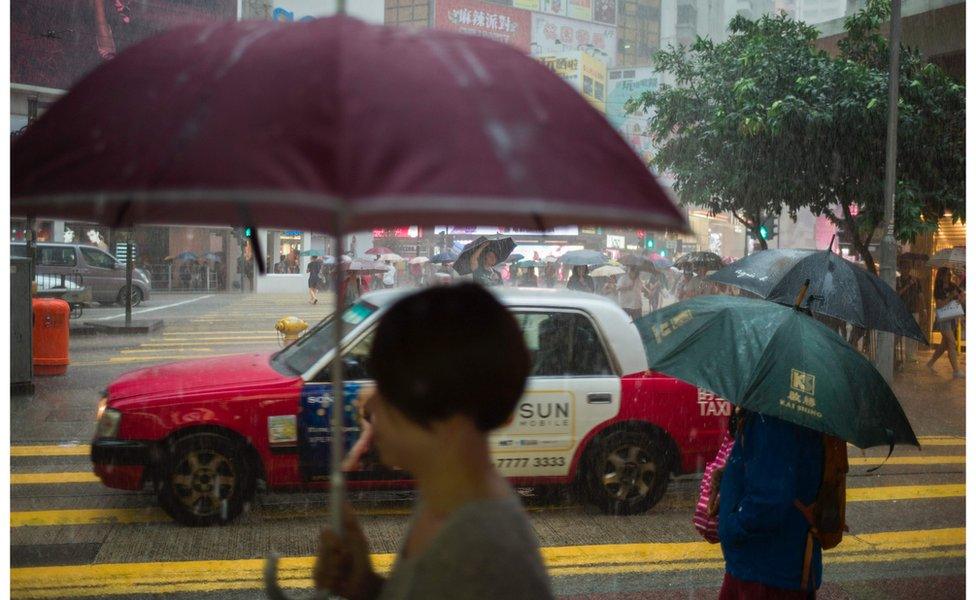 Pedestrians walk with umbrellas during a heavy downpour in Hong Kong's Causeway Bay district on 19 October 2016.