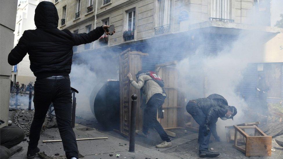 Demonstrators in Paris hide behind barricades and throw paving stones