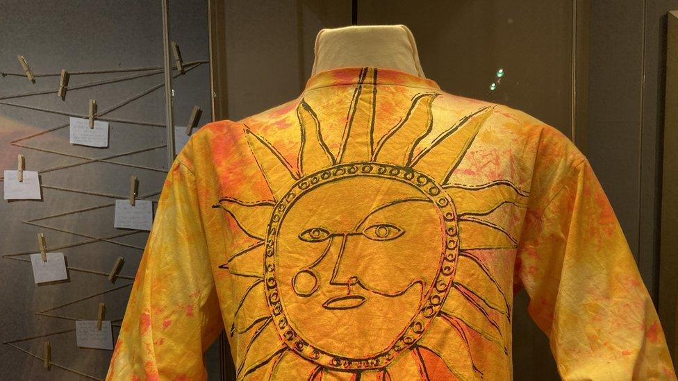 Yellow garment featuring a sun on display at the museum