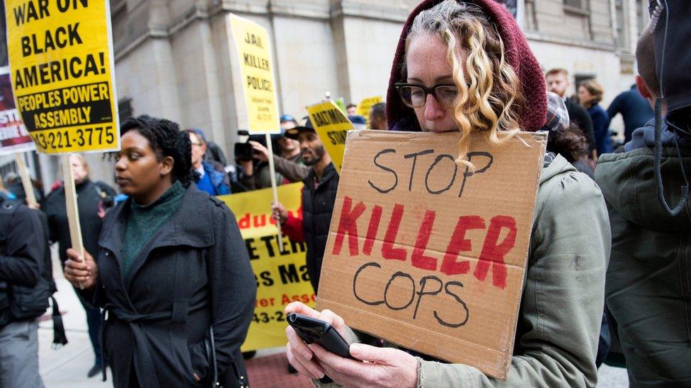 A woman holds a sign that reads "stop killer cops"