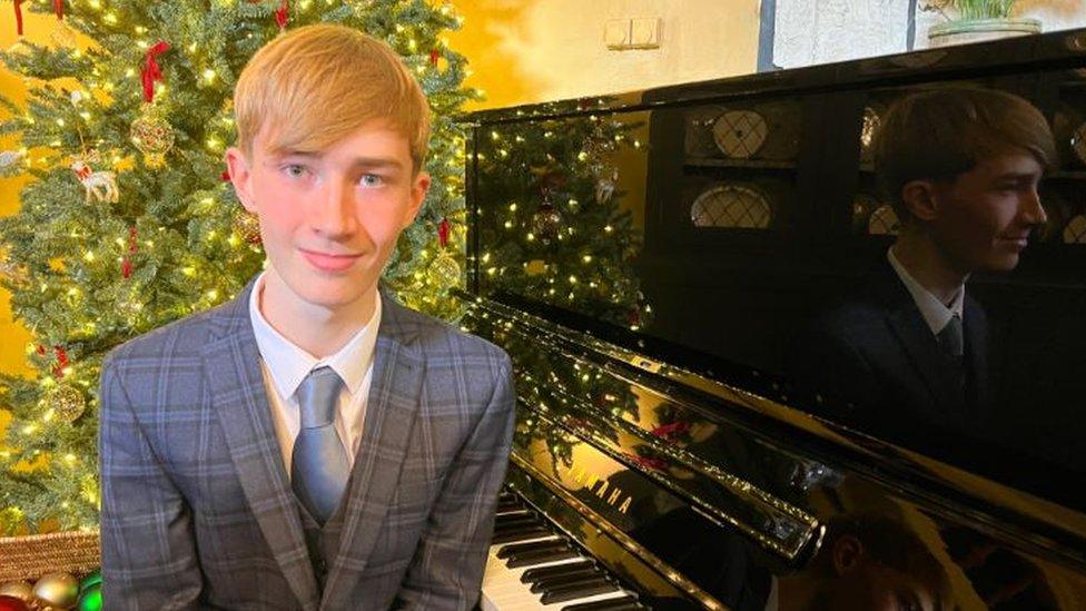 A boy sitting in front of the piano