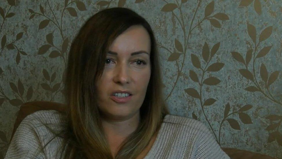 A woman sitting in front of leafy wallpaper