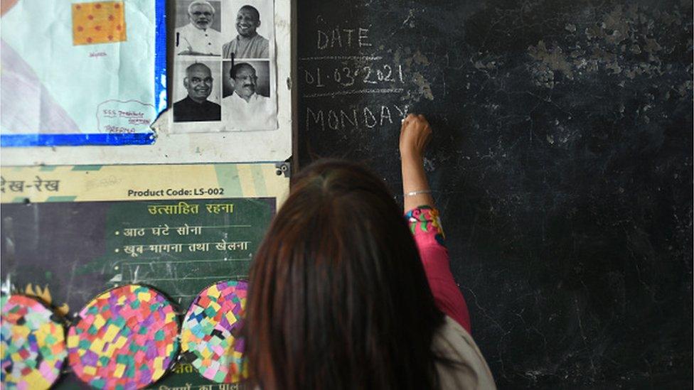 A teacher writes on a blackboard in a school in Uttar Pradesh