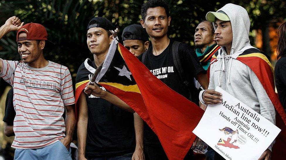 Protestors in East Timor hold flags and signs