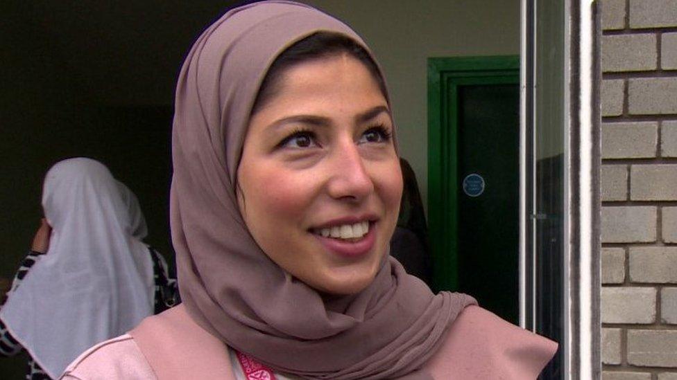 Hania smiles at the camera in front of a door