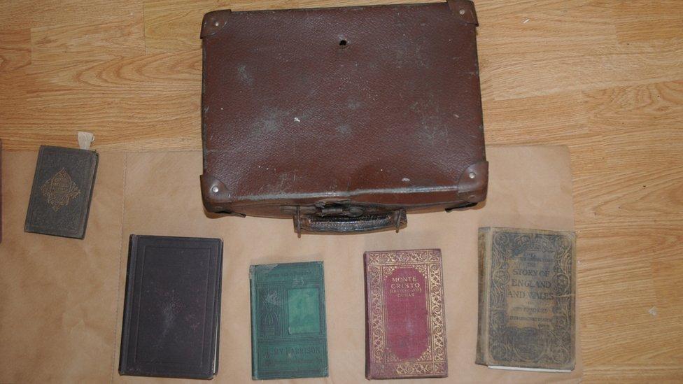 The books that were found, next to the suitcase they were found in