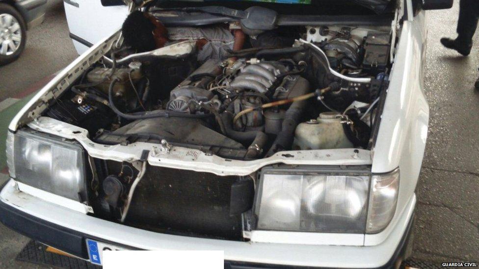 Guinea migrant next to car engine - Guardia Civil pic