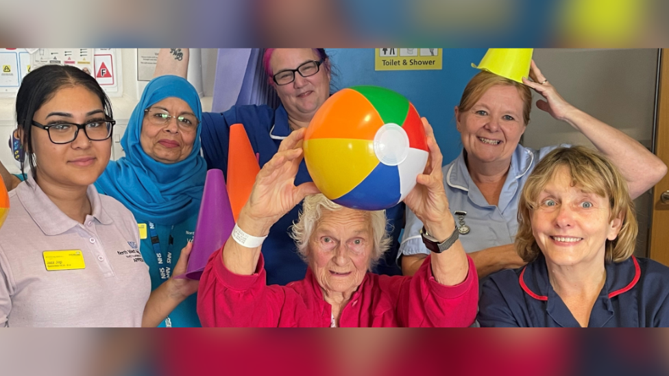 Hospital staff with a patient who is holding a beach ball on the ward