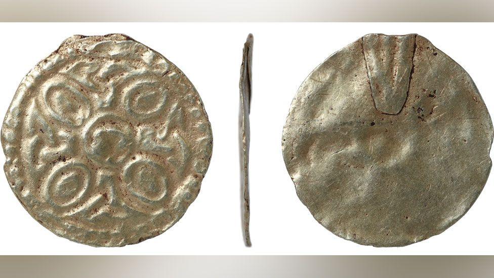 Three views of an early 8th Century gold round pendant. The view on the left is its front and with a circular boss in the middle, around it oval shapes and its edge has a border of raised dots; the middle view is from the side, showing how thin it is; the right view shows its reverse, a plain slightly dented gold disc with a section at the top where the hanging loop would have been attached.